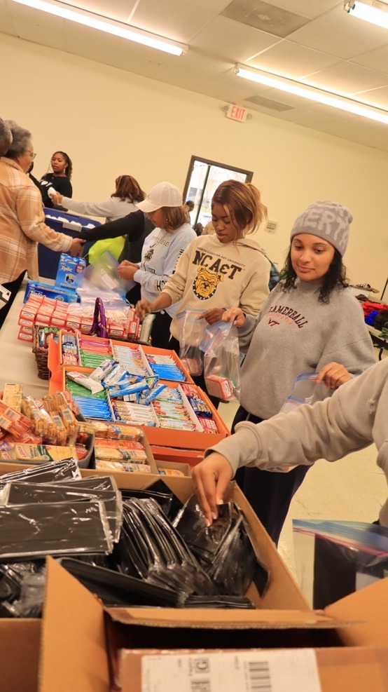 Volunteers assemble care packages at a community event, organizing school supplies and snacks to support local students in need.