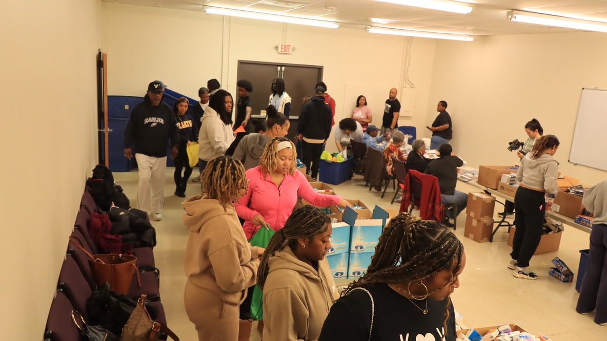 Volunteers assist in packing care packages inside a community space, fostering collaboration and support for local residents in need.