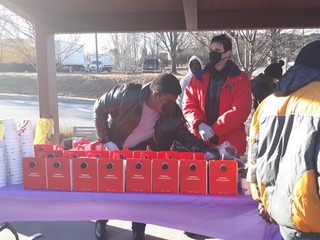 Volunteers distribute meals from red boxes at a community event, showcasing outreach efforts to support those in need during winter.