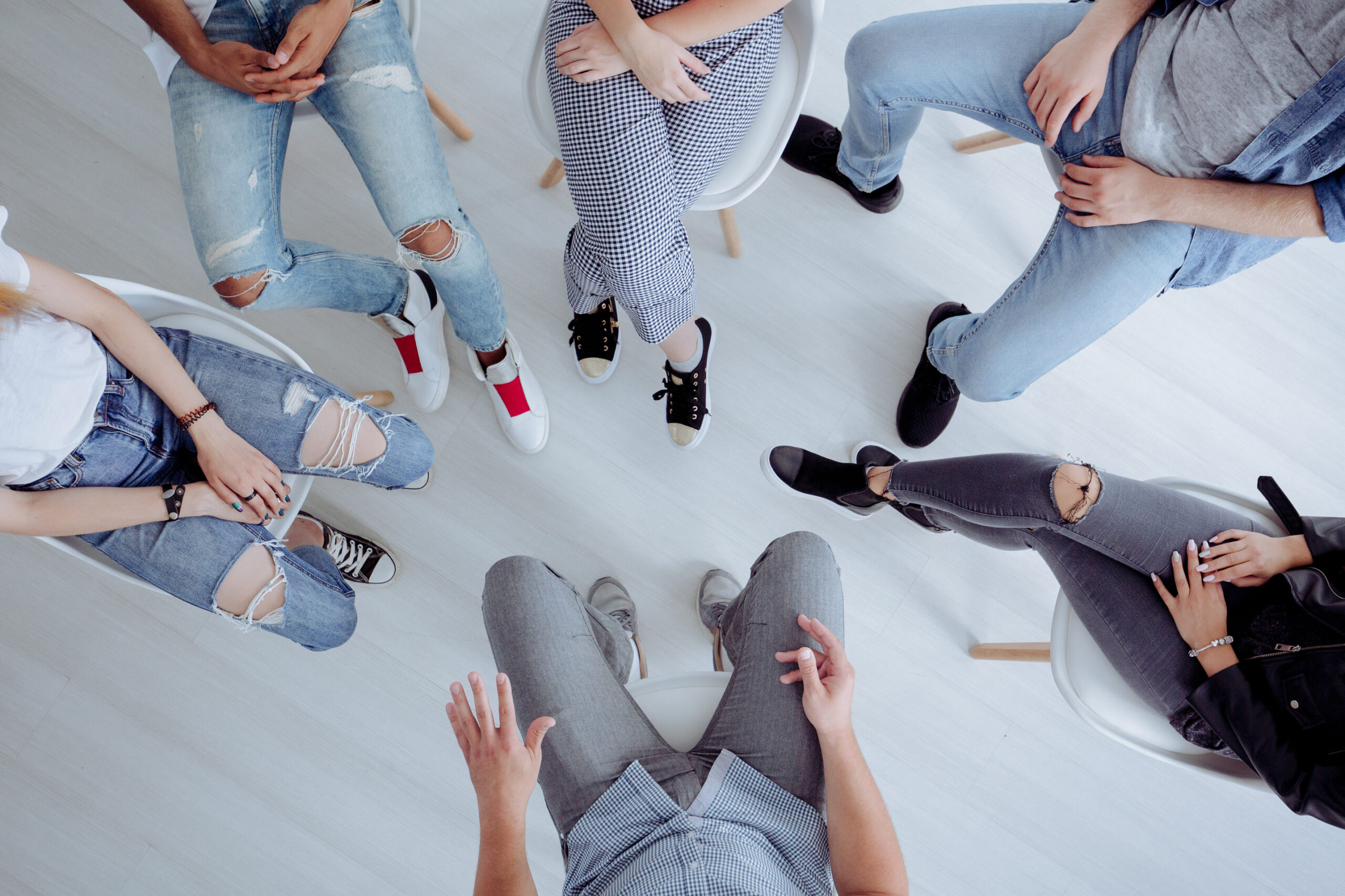 Aerial view of a diverse group of people in casual clothing, seated in a circle, engaging in discussion or conversation.