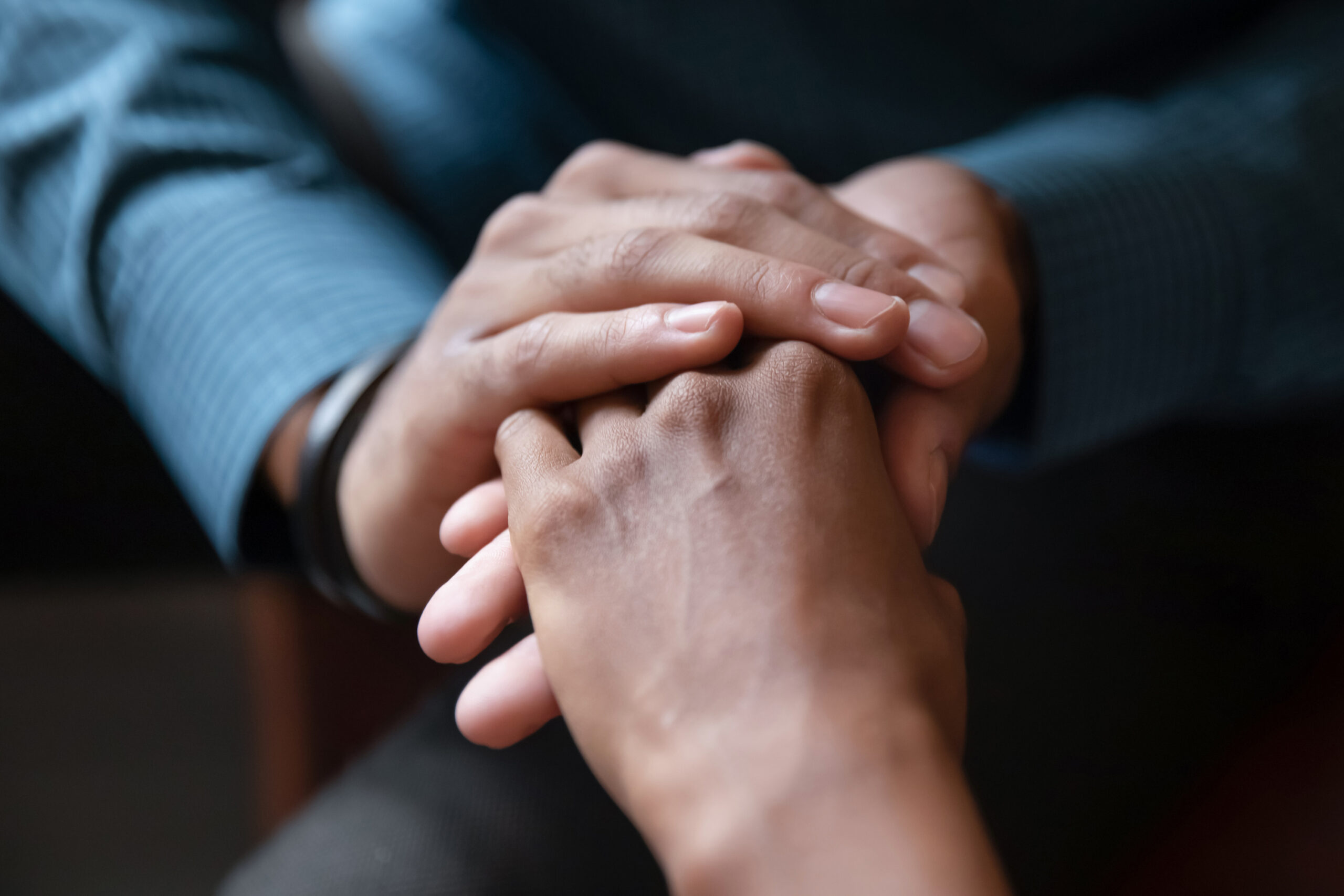Two hands gently clasped together, symbolizing support and connection, highlighting themes of empathy and companionship in a conversational context.